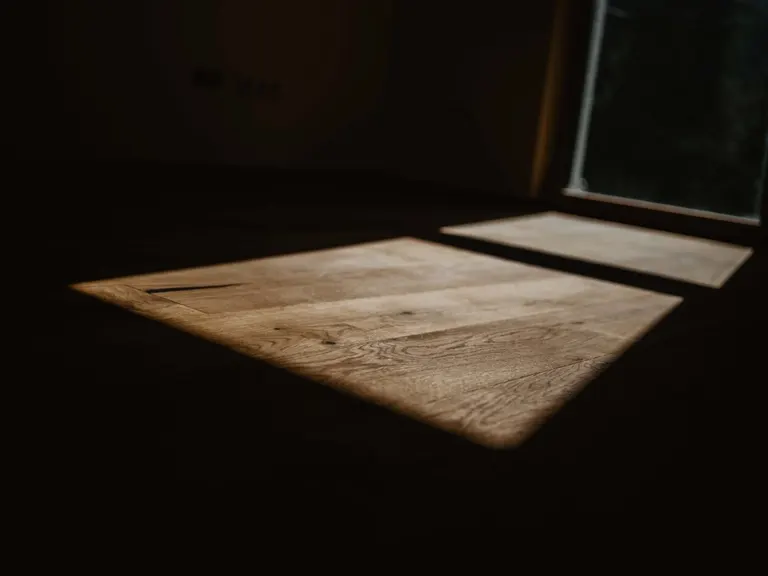 Sonnenlicht fällt auf einen fertigen Boden in einem dunklen Raum