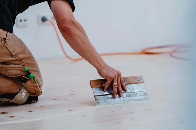 Öl wird mit dem Spachtel in den geschliffenen Holzboden eingearbeitet